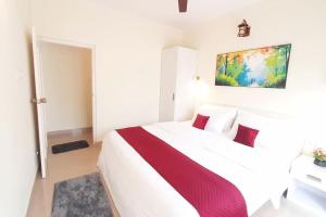 科尔瓦Colva Blossom 2BHK Apartment with Gym,Wifi and 5min walk to the famous Colva Beach的卧室里有一张白色的大床，上面有红色的枕头