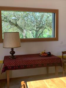 a window with a table with a lamp and a bowl of fruit at séjour nature au Shed - Sornay - Haute Saône 