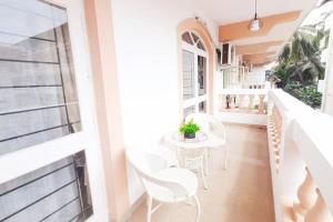 科尔瓦Colva Blossom 2BHK Apartment with Gym,Wifi and 5min walk to the famous Colva Beach的阳台配有白色的椅子和桌子