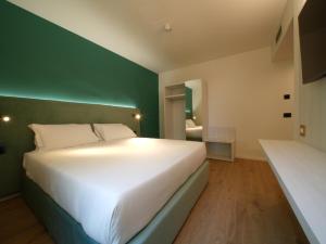 カスティリョンチェッロにあるCastiglioncello Suiteの緑の壁のベッドルーム1室(白いベッド1台付)
