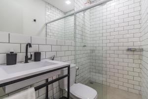 a white bathroom with a toilet and a sink at A CASINA: STUDIOS Vila Madalena - BECO DO BATMAN in Sao Paulo
