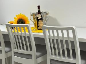 una mesa blanca con una botella de vino y 2 sillas en RESIDENZA GIOVANNI, en Contone