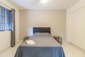 a bedroom with a bed with a blue bedspread at A CASINA: STUDIOS Vila Madalena - BECO DO BATMAN in Sao Paulo