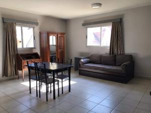 a living room with a couch and a table and chairs at Hôtel - Appartement " LES FLOTS BLEU " in Antananarivo