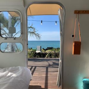 a bedroom with a view of the ocean through a door at BeachBoys - Retro Caravan AirStream in Jeju