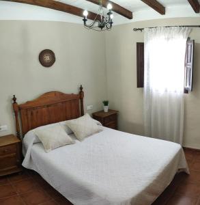 1 dormitorio con cama blanca y ventana en Casa Villazo I, en Almáchar