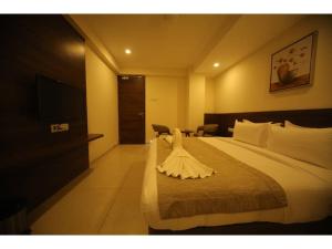 a hotel room with a large bed and a television at Hotel Jayson Metoda in Rajkot