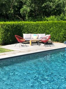 two chairs and a table next to a swimming pool at Maison d'hôtes kerwall in Malville