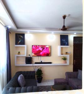 a living room with a couch and a tv on the wall at Leo's Enchanting homes in Mombasa