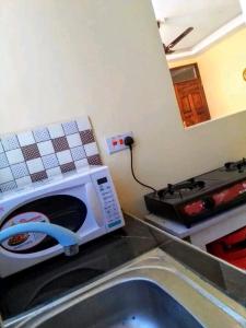 a kitchen with a stove and a microwave at Leo's Enchanting homes in Mombasa