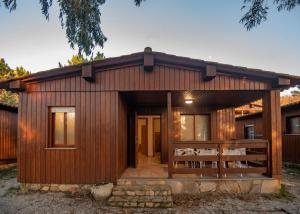 Cabaña de madera con terraza y mesa en Camping Rural Ria de Arosa 2, en Ribeira