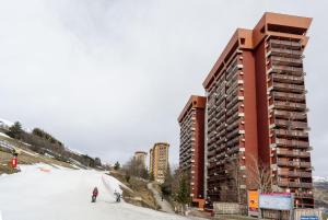 due persone che sciano sulla neve davanti a un edificio di Studio pied des pistes a Villarembert
