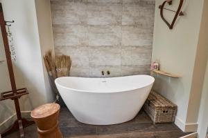 a white bath tub in a bathroom with a tiled wall at The Believe Boutique (Believe Bar & Bedrooms) in Redcar