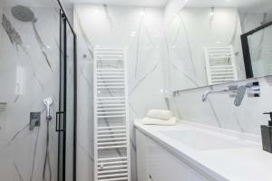 a white bathroom with a shower and a sink at Kallithea Modern Living with Designer Touch in Athens