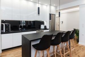 una cocina con armarios blancos y un bar con taburetes en Kallithea Modern Living with Designer Touch en Atenas