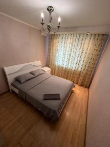 a bedroom with a bed and a chandelier at Квартира in Aktobe