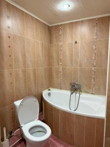 a bathroom with a toilet and a bath tub at Квартира in Aktobe