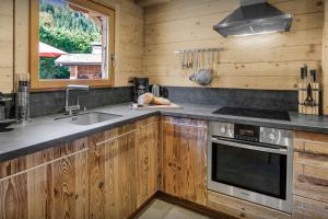 a kitchen with wooden cabinets and a sink and a stove at Cristal des Neiges La Clusaz - OVO Network in La Clusaz