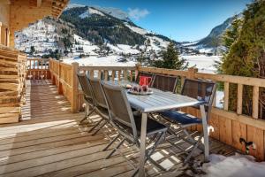 a wooden deck with a table and chairs on it at Cristal des Neiges La Clusaz - OVO Network in La Clusaz