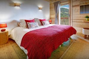um quarto com uma cama grande e um cobertor vermelho em Chalet Lydie Manigod - OVO Network em Manigod