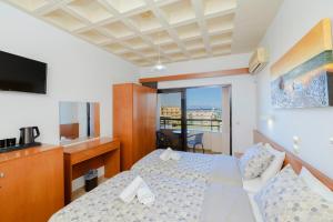 a hotel room with two beds and a television at Heleni Beach Hotel in Ialyssos