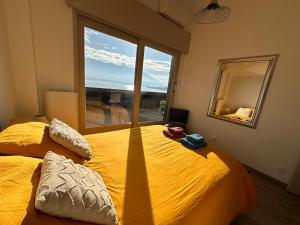 een slaapkamer met een geel bed en een groot raam bij Rooftop pieds dans l’eau, terrasse, parking sécu in Le Bourget-du-Lac