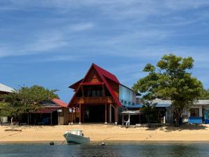 a building on the beach with a boat in the water at MC Bunaken Inn & Dive in Bunaken