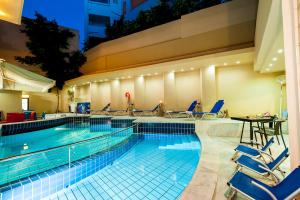 a swimming pool with blue chairs and a table at Elina Hotel Apartments in Rethymno