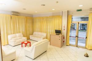 uma sala de estar com duas cadeiras brancas e uma televisão em Hotel Galileo em Rimini