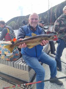 a man sitting on a boat holding a fish at Burtonport fishing trips in Dungloe