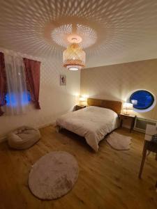 1 dormitorio con cama y lámpara de araña en Charmant T3 à côté des Thermes en Luxeuil-les-Bains