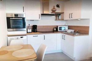 a kitchen with white cabinets and a wooden table at Maisonnette pour 2 personnes - Vue mer - Plage à 100 mètres in Ploubazlanec