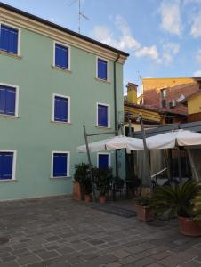 un edificio blanco con sombrillas y un patio en Casa del Marinaio - Agenzia Cocal, en Caorle