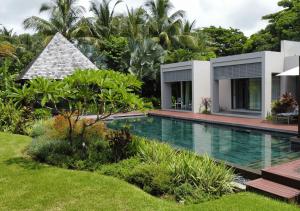 a swimming pool in front of a villa at Villa Fairways - Private, Golf & Luxe in Centre de Flacq
