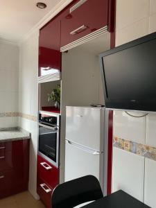 cocina pequeña con nevera y TV en Apartamento en Gijon, en Gijón