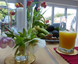 una mesa con un jarrón de flores y un vaso de zumo de naranja en The Sanctuary, en Richmond