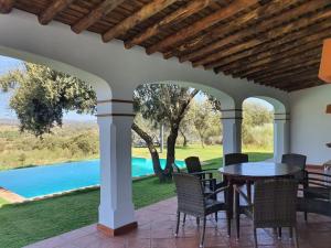 een patio met een tafel en stoelen en een zwembad bij CASA RURAL MONTE DE AJUDA in Olivenza
