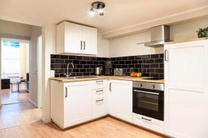 a kitchen with white cabinets and a black tile wall at SPACIOUS Two BR plus AC plus SelfCheckIn in Berlin +11 photos