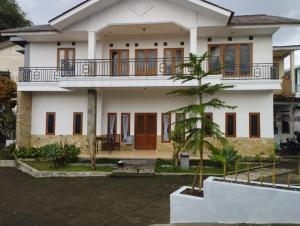 uma casa com uma palmeira em frente em Villa bhifa Puncak em Bogor