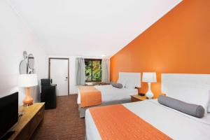 um quarto de hotel com duas camas e uma parede laranja em Howard Johnson by Wyndham Wilmington em Wilmington