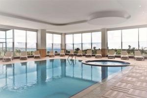 a pool in a hotel with chairs and windows at Ramada by Wyndham Tekirdağ in Tekirdag