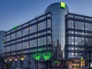 a tall glass building with a green sign on it at ibis Styles Paris Bercy in Paris