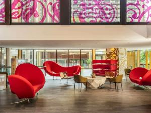- un hall avec des chaises rouges, des tables et des fenêtres dans l'établissement Mercure Paris Centre Tour Eiffel, à Paris