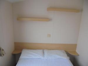 a small bedroom with a bed with white sheets at 8 Berth on Coastfields Ingoldmells (Vacation) in Ingoldmells