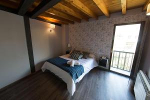 a bedroom with a bed and a large window at Rustik Hostal Rural in Molinaseca