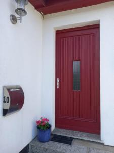una porta rossa su un edificio con una pentola di fiori di Ferienhaus Loissin a Loissin