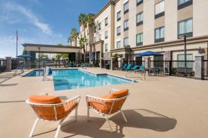 a swimming pool in front of a building with chairs at Hampton Inn & Suites Phoenix North/Happy Valley in Phoenix