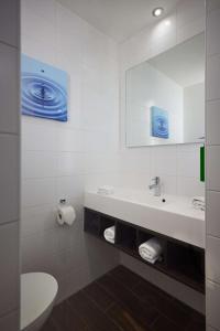 ein weißes Badezimmer mit einem Waschbecken und einem Spiegel in der Unterkunft Hilton Garden Inn Leiden in Leiden