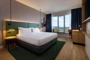 a hotel room with a large bed and a window at Hilton Garden Inn Leiden in Leiden