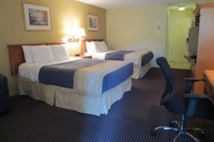 a hotel room with two beds and a chair at Super 8 by Wyndham Gananoque - Country Squire Resort in Gananoque